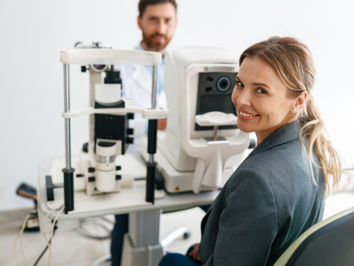 Smiling woman patient awaits vision test at opticians shop on the man optometrist background