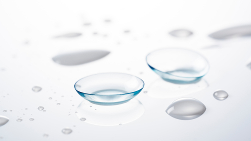 Soft contact lenses placed on a white background with water droplets. Image of a contact lens.